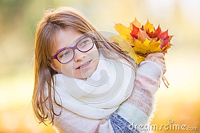 Autumn. Portrait of a smiling young girl who is holding in her hand a bouquet of autumn maple leaves. Stock Photo