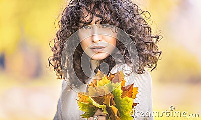 Autumn portrait of young woman with curly hair and bouquet of maple leaves Stock Photo