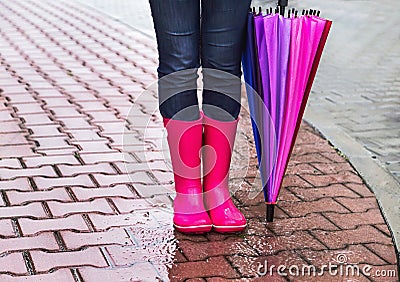 Autumn. Protection in the rain. Woman (girl) wearing pink rubber boots and has colorful umbrella. Stock Photo