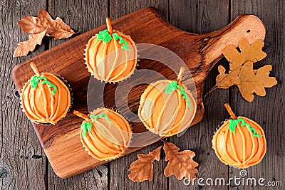 Autumn pumpkin cupcakes on a wooden serving platter over rustic wood Stock Photo