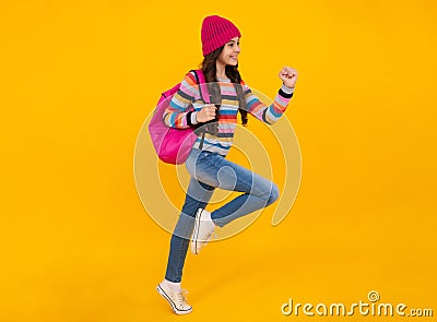 Autumn school holiday. Back to school. Teenager schoolgirl in autumn clothes on yellow studio background. Jump Stock Photo