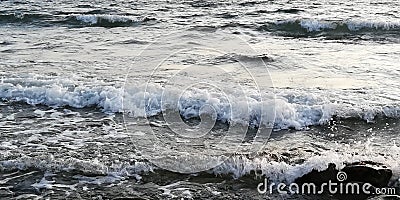 Autumn cold sea at sunset. White foam on the crest of the sea wave. Waves and rocky beach. Romantic, disturbing, harsh seascape. Stock Photo