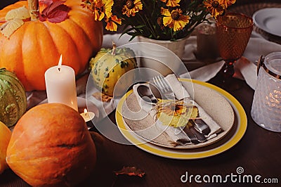 Autumn traditional seasonal table setting at home with pumpkins, candles and flowers Stock Photo