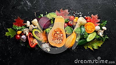 Autumn vegetables on a black stone background: Pumpkin, tomatoes, corn, cucumber, onion, carrot. Autumn food. Stock Photo