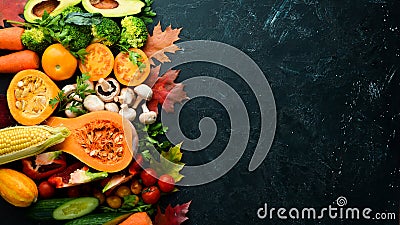 Autumn vegetables on a black stone background: Pumpkin, tomatoes, corn, cucumber, onion, carrot. Autumn food. Stock Photo