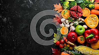 Autumn vegetables and fruits on a black stone background: Pumpkin, tomatoes, corn, pomegranate, persimmon, apple. Stock Photo