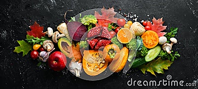 Autumn vegetables and fruits on a black stone background: Pumpkin, tomatoes, corn, pomegranate, persimmon, apple. Stock Photo