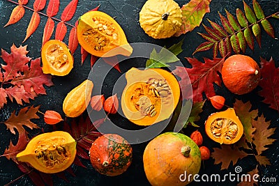 Autumn vegetables. Pumpkin with pumpkin seeds and autumn leaves. flat lay. On a black stone background. Top view. Stock Photo