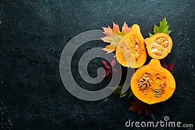 Autumn vegetables. Pumpkin with pumpkin seeds and autumn leaves. flat lay. On a black stone background. Top view. Stock Photo