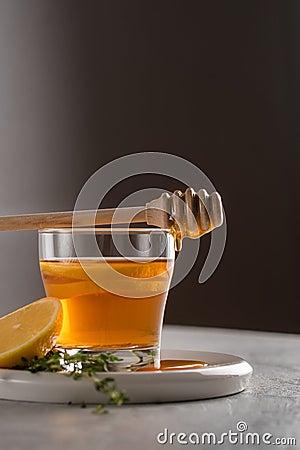 Autumn and winter traditional drinks. Warming hot tea with lemon, honey and thyme in backlight. Healthy drink Stock Photo