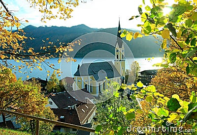 Autumnal view through branches to schliersee lake and church Stock Photo