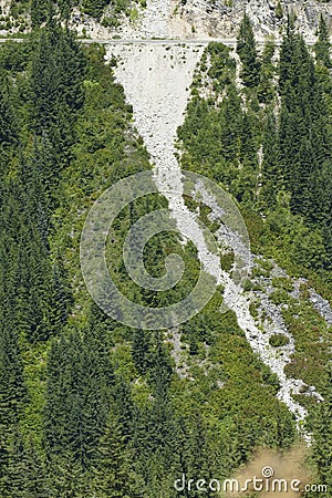 Avalanche track on steep mountainside above a road Stock Photo