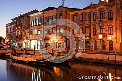 Aveiro, Portugal - April 2019: Typical Moliceiro boats at the central water canal and Art Nouveau buildings, at night. Editorial Stock Photo