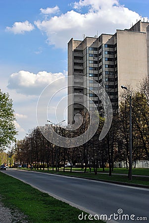 Avenue of trees and street lights along road with high storey office building in city, blue sky Stock Photo