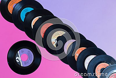 Avetrana, Italy, April 22, 2019 Old vinyl records on a two-color background: pink and lilac, retro concept, pop culture Editorial Stock Photo