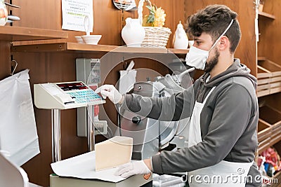 Avetrana, Italy, - Marth 19, 2020. Salesman is serving a costumer a cheese, wearing medical mask and gloves protection during Editorial Stock Photo
