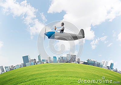 Aviator driving propeller plane above city Stock Photo