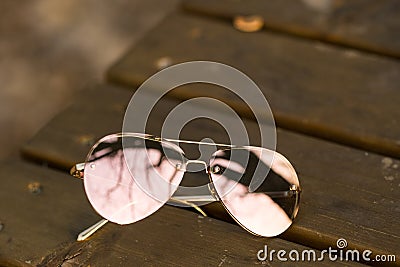 Aviator Sunglasses model with big pink lenses reflecting the sun in a summer day closeup . Selective focus Stock Photo