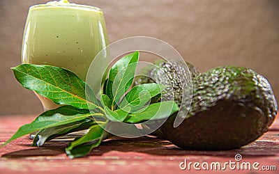 Avocado cream on the wooden surface with fresh fruits and leaves Stock Photo