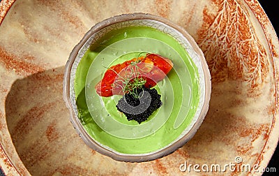 Avocado cream with minced tomato and caviar. Guacamole sauce in handmade ceramic bowl. Modern food - avocado dip. Healthy Stock Photo