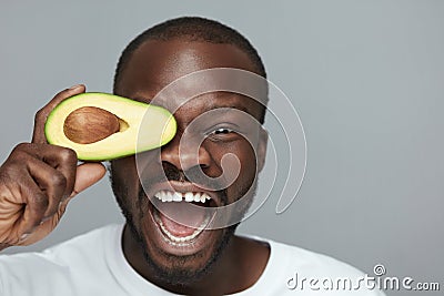 Avocado Facial Treatment. Skin Care With Natural Vitamins. Male African Model Holds Fresh Fruit Near Face. Stock Photo