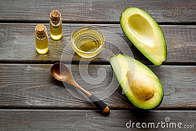 Avocado oil for cosmetology. Sltill lfe with half of fruit and bottles on wooden background Stock Photo