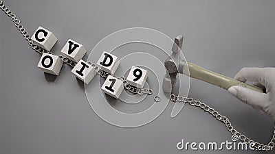 Awareness of pandemic issue concept - COVID19 text on wooden blocks with broken chain and hammer with hand holding it Stock Photo