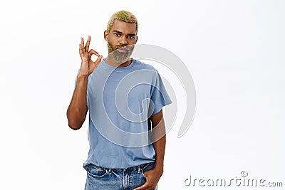 Awesome, amazing product. Excited smiling black man with yellow beard and hair, shows okay, ok sign, recommends store Stock Photo