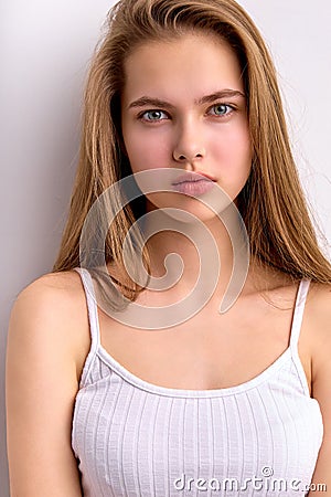 Awesome caucasian female with natural long brown hair posing at camera, in white undershirt Stock Photo