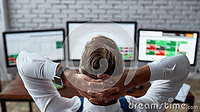 An awesome financial state of mind. Rear view of middle-aged trader sitting back in front of pc and analyzing stock Stock Photo