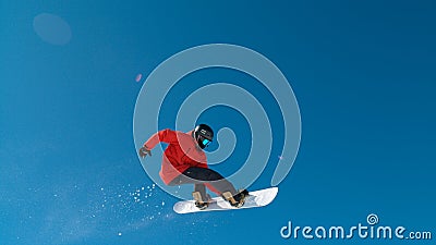 Awesome male snowboarder riding on a sunny day doing a trick high up in the air. Stock Photo