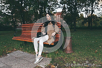 Awesome portrait of young lady, sitting on the wooden bench at the park.Soft colours, awesome place Stock Photo