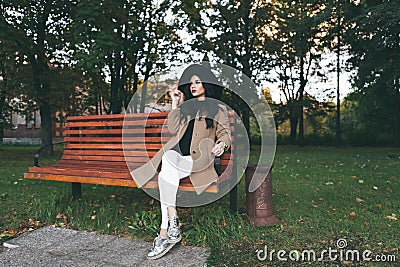Awesome portrait of young lady, sitting on the wooden bench at the park.Soft colours, awesome place Stock Photo