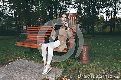 Awesome portrait of young lady, sitting on the wooden bench at the park.Soft colours, awesome place Stock Photo