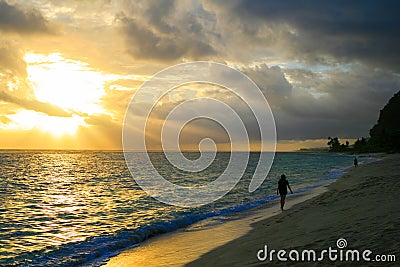 Awesome sunset beach walk after tropical storm, golden sun rays sunbeams opening dark cloudy sky Stock Photo