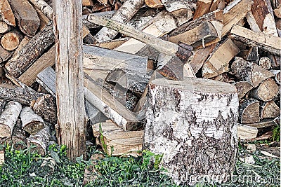 An ax in a wooden beam against the background of a pile of wooden firewood. Stock Photo