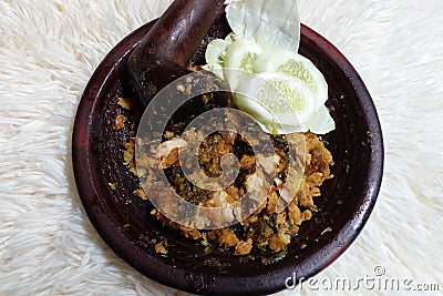 Ayam geprek sambal ijo. Fried chicken mixed with green chili sauce placed in clay mortar. Stock Photo