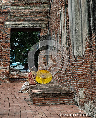 Beautiful Thai girl in traditional dress custume sit rest at Wat Ratchaburana Editorial Stock Photo