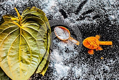 Ayurvedic remedy for sour throat consisting of betel leaves, turmeric, and salt on a black wooden surface. Stock Photo