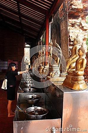 Ayutthaya, Thailand - April 29, 2014. Woman in the Buddhist temple lights a lighter as an offering Editorial Stock Photo