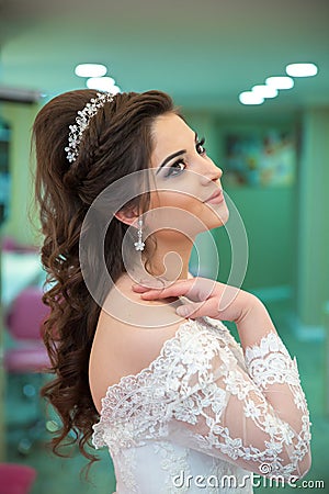 The bride puts her hand on her shoulder and takes a picture at the wedding. Wedding photo session in a beauty salon.The bride put Editorial Stock Photo
