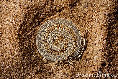Golden antique aztec coin in sand. Stock Photo