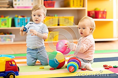 Babies boy and girl playing on floor with toys. Kids toddlers in creche or nursery Stock Photo