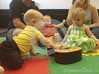 Babies in music class crawl to guitar. Editorial Stock Photo