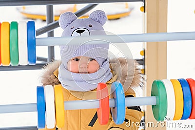 A baby aged 12-17 months became interested in colorful wooden bills on the playground in winter Stock Photo