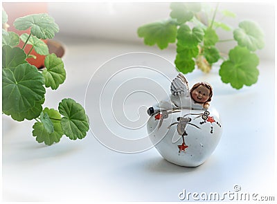 Baby angel statuette staying on the heart. Christmas Angel near to the windows Stock Photo