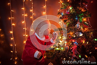 The baby around the Christmas tree with lights Stock Photo