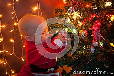 The baby around the Christmas tree with lights Stock Photo