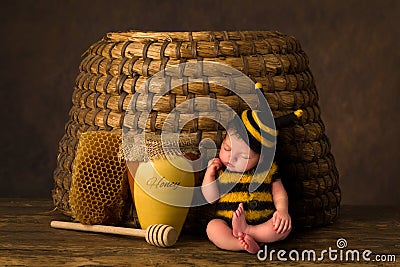 Baby in bee outfit and real beehive Stock Photo