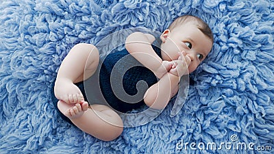 Baby in a blue knitted jumpsuit clothes. Lying on blue fur Baby in a blue knitted jumpsuit clothes. Lying on blue fur